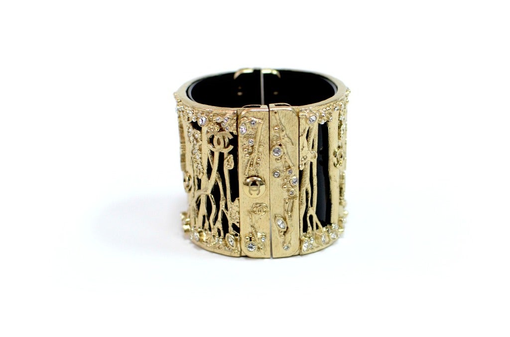 Authentic Vintage Chanel Cuff Bracelet with small Chanel logos and Crystals set in Gold Hardware.

Measurements: 7