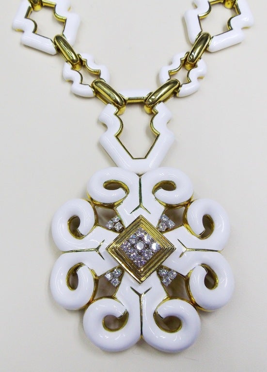 The necklace composed of openwork fancy-shaped links applied with white enamel, the inner links outlined in polished gold, joined by polished gold bar links, suspending a stylized scrolled pendant applied with white enamel, with similar gold trim,