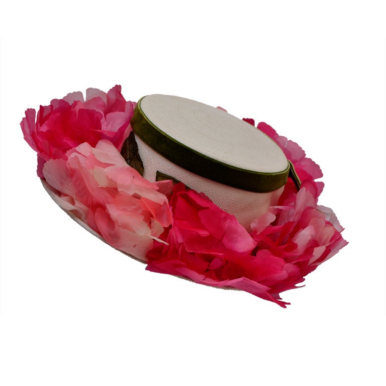 A beautiful vintage Elsa Schiaparelli floral boater hat with original hat box. The style is considered the boater shape, and is a tightly woven cream color hat. The hat is designed with various shades of light to hot pink fluffy satin flowers all