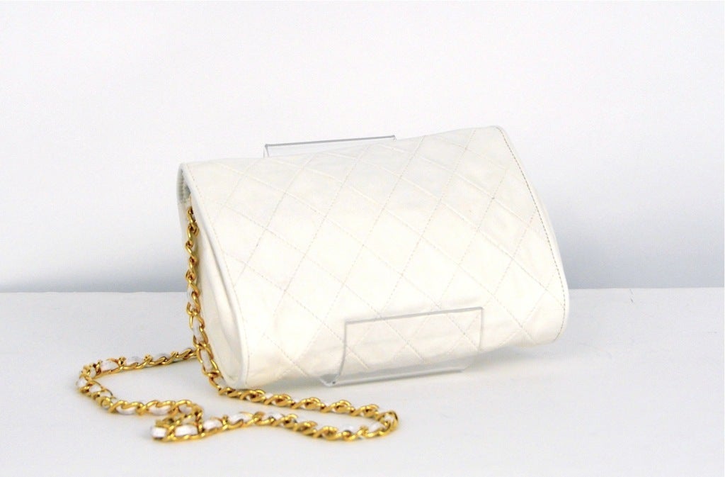 White leather quilted clutch handbag with single leather and chain strap. Envelope shape single flap at front with hammered studs along edges.