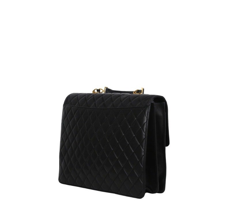 Black quilted lambskin attaché / computer bag. Large gold Mademoiselle closure with short leather handle. Duel compartments with 3 zip side pockets on inside.