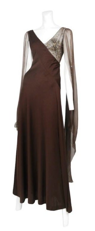 Dark chocolate jersey gown with shear chiffon whimsical fly away sleeves and bead & sequin detailing at bust.