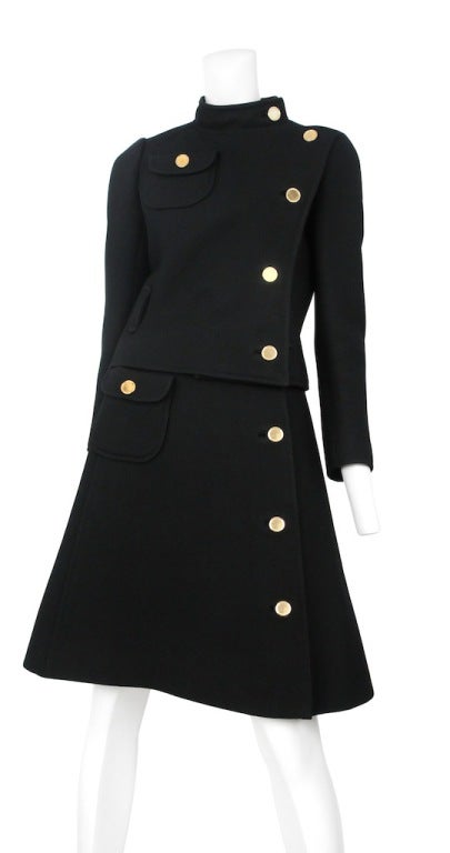 Midnight black 2pc wool ensemble. Classic Courreges piece. 
Brass colored flat head buttons and high placed pocket above bust. Buttons continue to skirt with matching pocket.