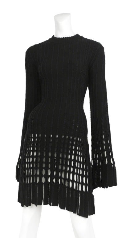 Black textured knit mini dress with cut-out and fringe detailing at cuffs and hem.