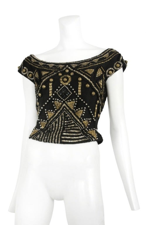 Heavily encrusted brass colored bead & tact top  that falls off the shoulder into a cap sleeve and side zip closure.