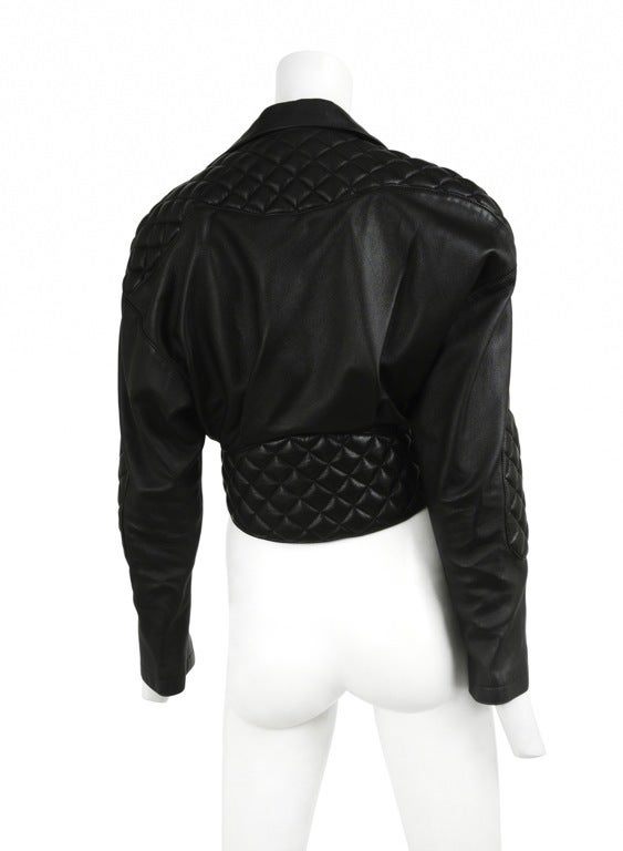 Black leather open front moto jacket. Puffy quilted leather elbow patches and shoulders. Tie front closure.
