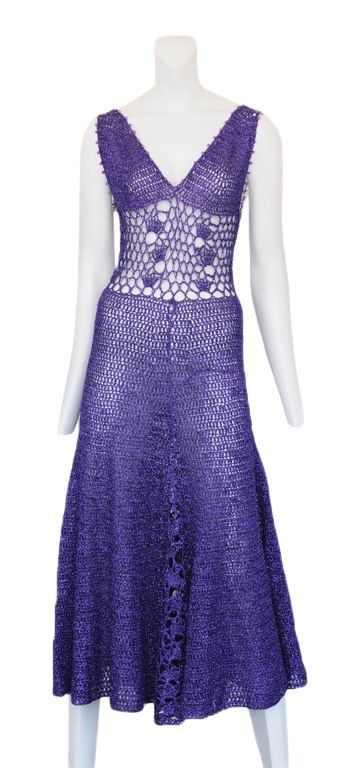 Metallic purple crocheted cocktail dress with a loose weave detail at waist and down the center front of skirt. Small purple bead trim hug the hem of the bodice. c.1970's