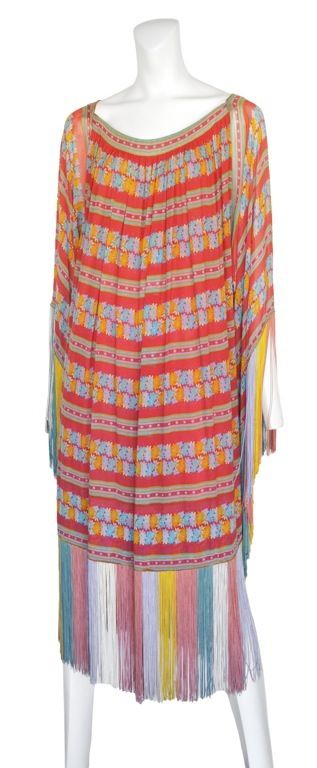 Chiffon caftan with floral print and exquisite muted multi color long fringe detailing at hem and sleeve.