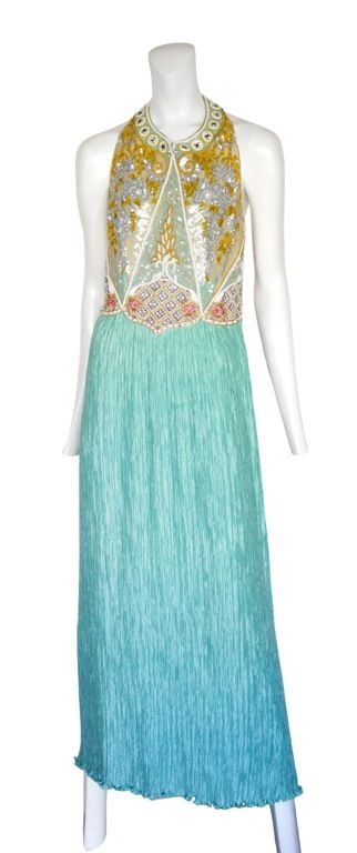 Long vibrant gown with extensive bead work on halter bodice and open wide back. <br />
The skirt is done in  a bright aqua blue with Mcfadden's trademark pleats.  Zip closure at back.