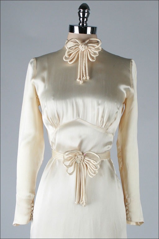 vintage 1930's dress

* ivory silk satin
* gorgeous triple bow detail and neck
* bow repeated in detachable belt
* button closure sleeves
* side zipper
* bias cut detailing
* open slit in back

condition | excellent - a few inconspicuous