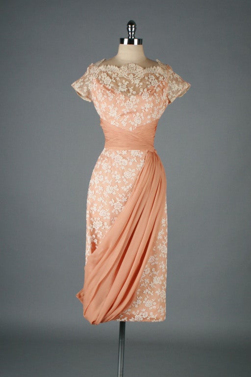 Amazing 1950's dress from Robert-Martin.  Gorgeous ivory lace over peach/nude net backing and peach acetate lining.  Waist wrapped in silk crepe with a sash that dips across the skirt to the right hem where it ends with a tidy little bow.  Weighted