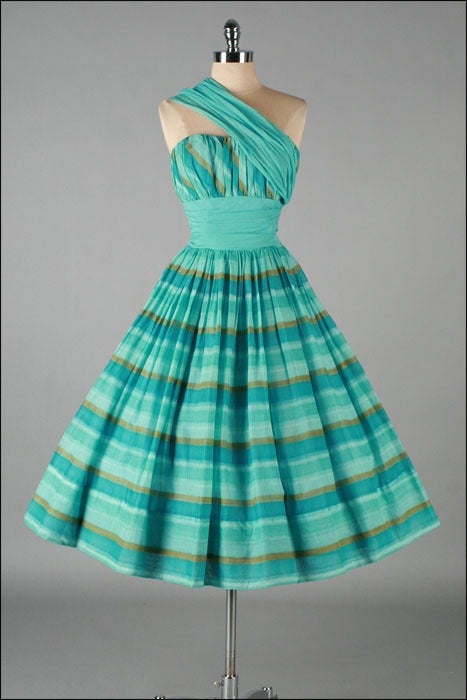 Vintage 1950's dress

* Aqua and gold striped cotton
* Cotton lining
* Attached organza sash can be worn over either shoulder
* Full skirt
* Metal back zipper
* Shelf bust with stays
* Narrow straps can be tucked in for