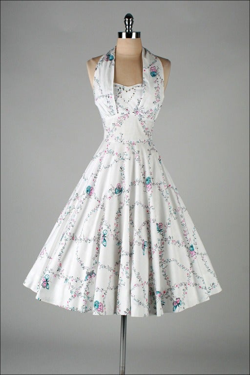 vintage 1950's dress

* white cotton
* adorable butterfly and floral print
* halter neck
* rhinestone and pearl heart shaped design
* side stays at bodice
* full skirt
* metal side zipper
* by Miami Guild

condition | excellent - just a
