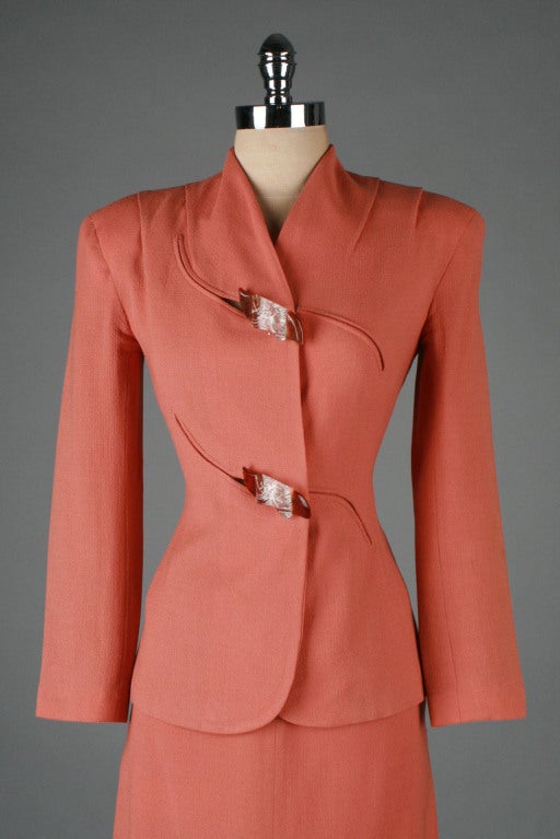 1940's Lilli Ann suit.  Terra cotto rayon crepe with silk satin lined jacket.  Curved hem in front.  The most amazing bakelite and lucite buttons that are a perfect accompaniment to the sculptural details and button holes on the jacket. 