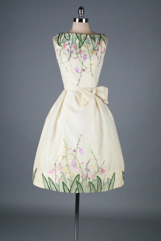 Amazing 1950's cocktail dress.  Ivory organza over acetate and tulle linings.  Detailed in gorgeous and vivid floral embroidery.  Side waist bow.  Cupcake style skirt.  Metal back zipper. 

Excellent condition.

Fits like size small.

Length