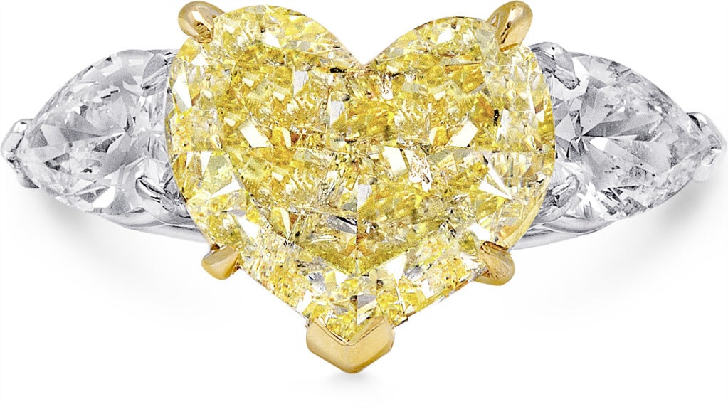 Engagement ring, 5.01 carat Heart-cut Fancy Intense Yellow diamond EGL-USA certified I1 clarity flanked by 1.33 carat Pear-cut diamonds. Set in platinum and 18k yellow gold.