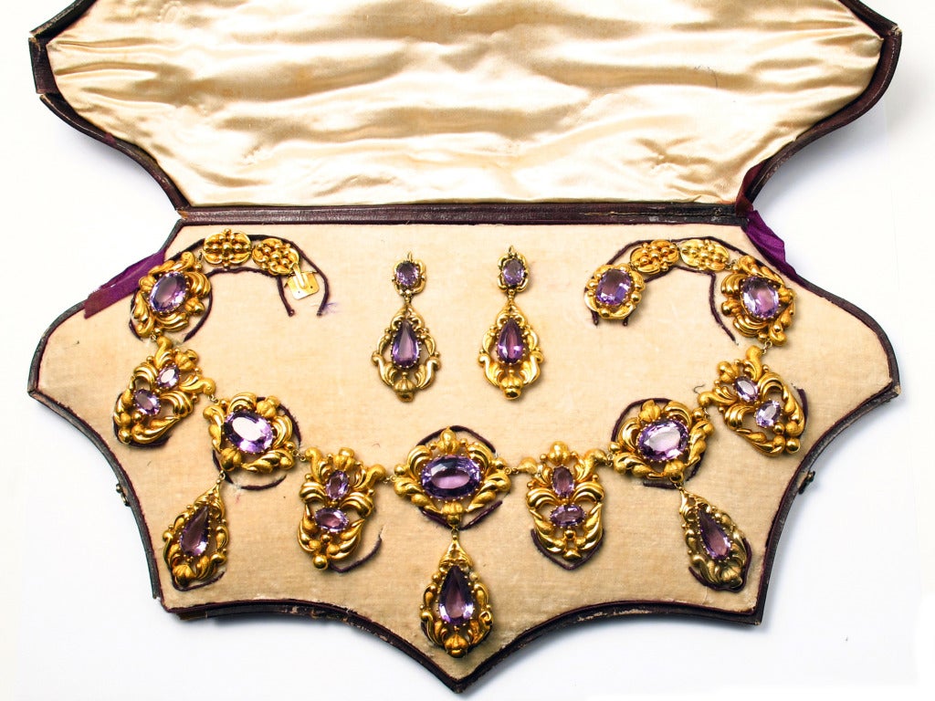 A georgian repoussé yellow gold and amethyst parure comprising a necklace and a pair of earrings. England, 1830 c.a. In original fitted box.