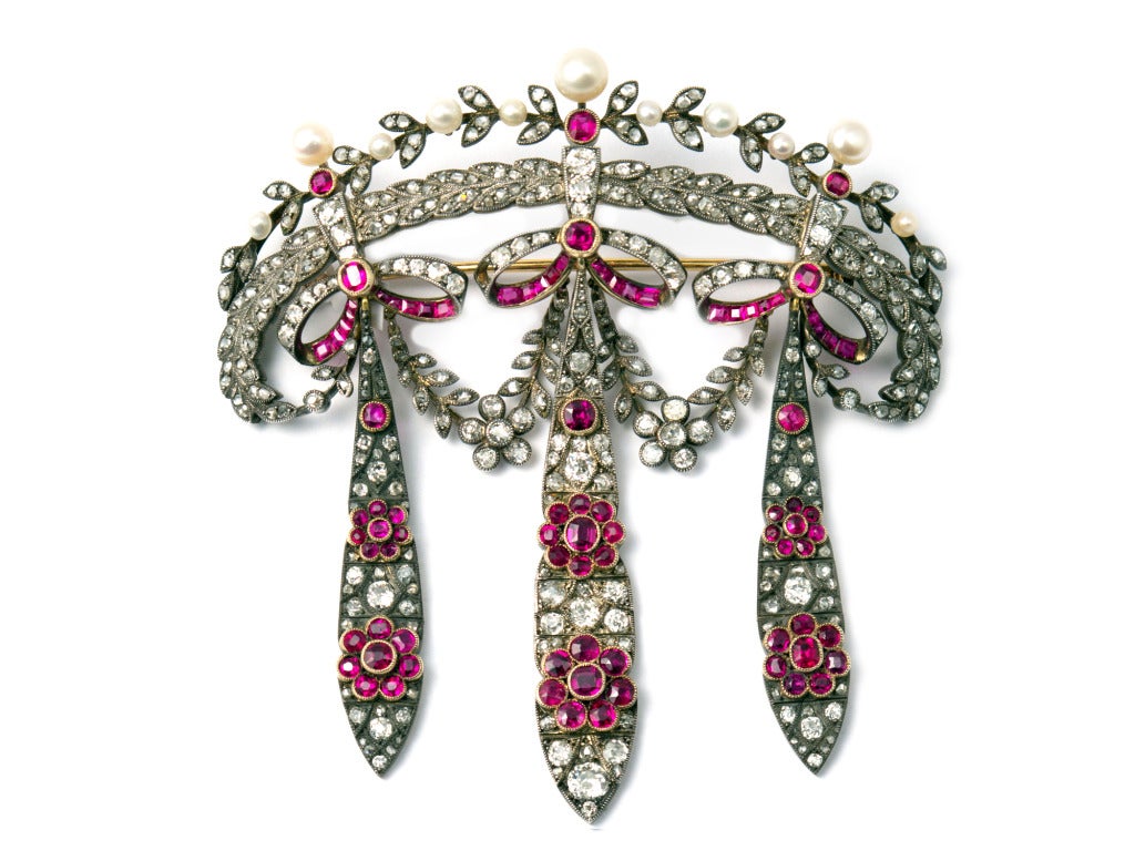 An antique silver topped yellow gold corsage brooch with diamonds, rubies and natural pearls. The side pendants can be transformed into earrings. Around 1880.