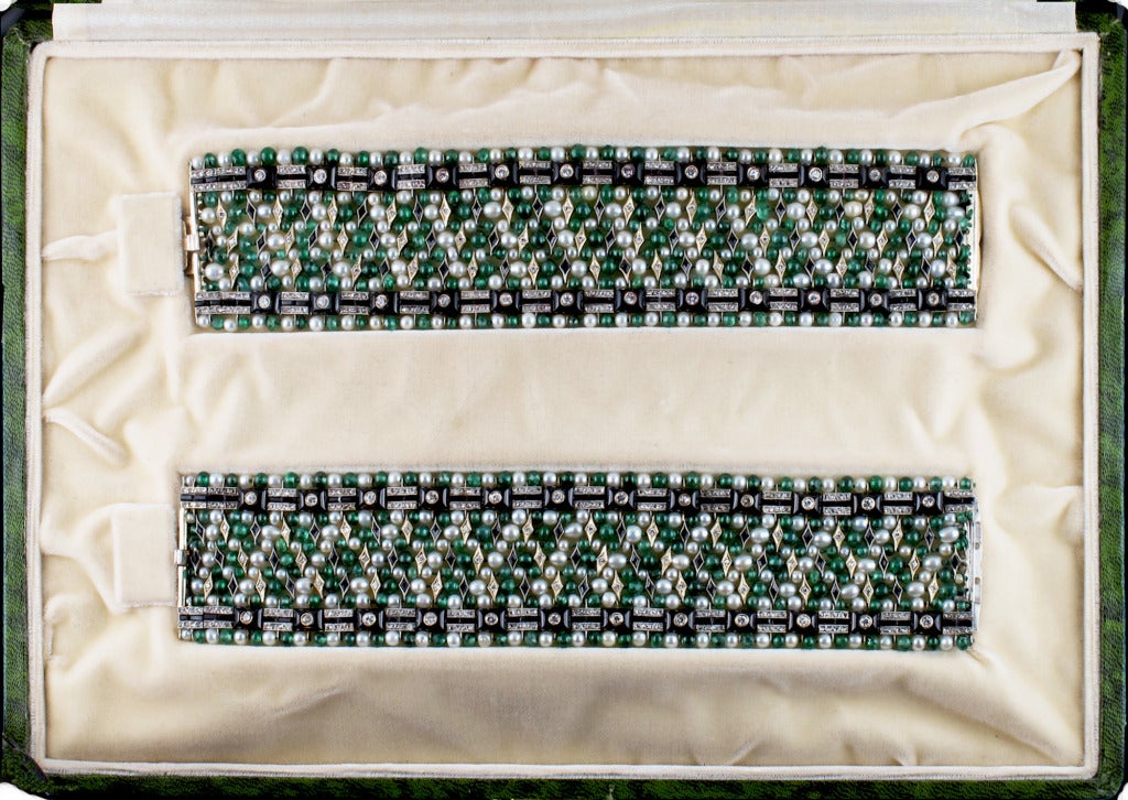 A magnificent pair of Art Deco emerald, pearl, onix and diamond twin bracelets. Composed as a woven fabric that alternates emerald beads, natural pearls, kite-shaped elements with onyx and diamonds. Mounted on gold and platinum. The bracelets can be