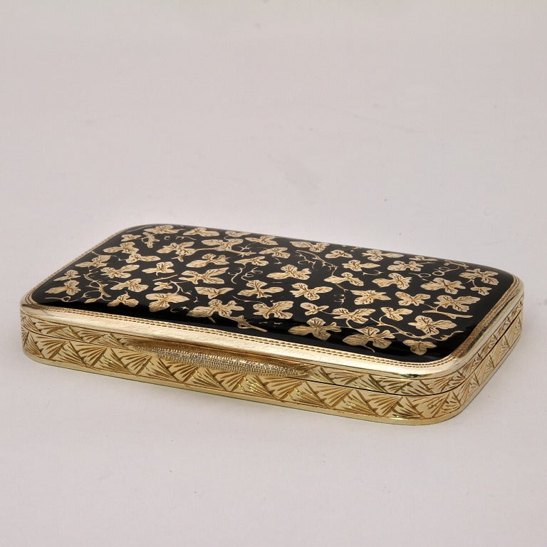 An amazing silver gold plated small box with fine decoration of golden grape leaves engraved on a black fired enamel, with rounded corners all around, and at the bottom it is wonderfully hand engraved with flowers and leaves.

It is really a small
