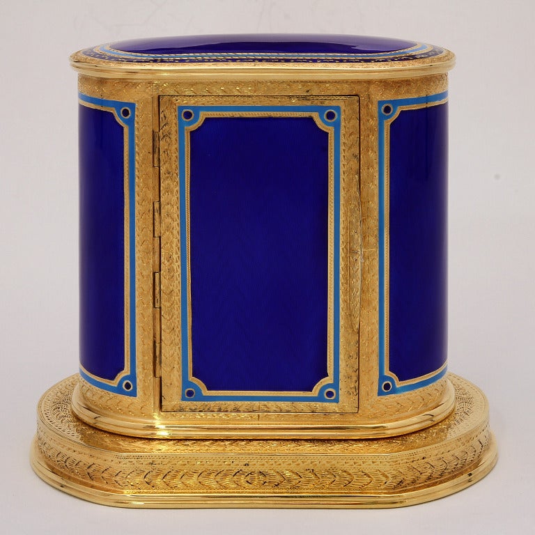 Empire table clock with Swiss pendulum, Matthew Norman alarm, gold plated silver with fired royal blue enamel and hand chiselled empire base and top decoration.

A very classical masterpiece, to be put on our desk with precious picture frames of