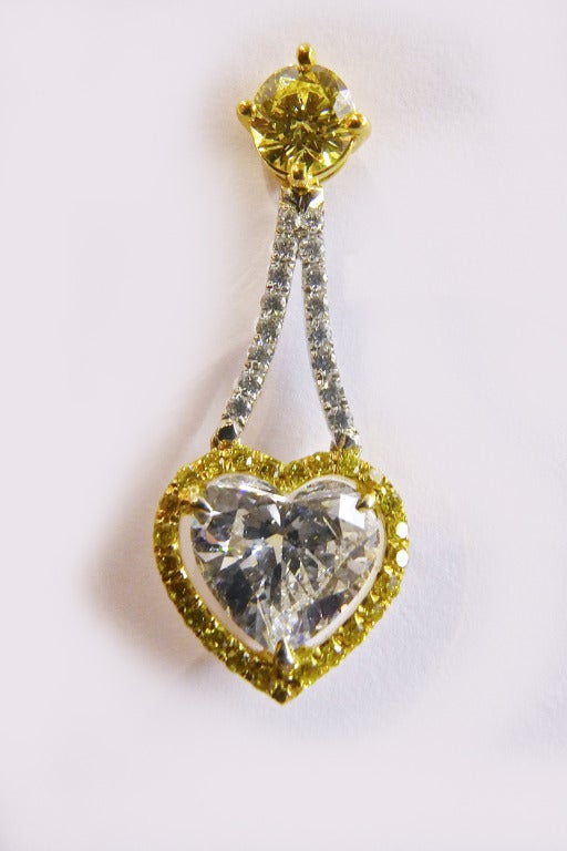 Delightful platinum and yellow gold heart shaped diamonds earrings.
All the stones (brilliant-cut diamonds) of each earring are in contrast with the other earring.
The center hearts are 1,52 carat F-VS2 and 1,51 carat Fancy yellow-SI2 certified by