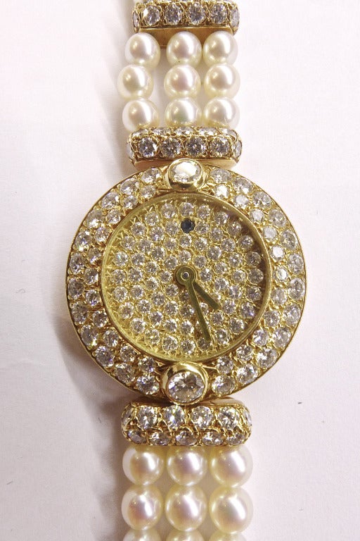 18k yellow gold Boucheron lady's bracelet watch, circa 1980s. The dial and bezel are all set with diamonds, the bracelet is made of three rows of white Akoya pearls decorated with yellow gold links set with diamonds. Manual-wind movement. Length: