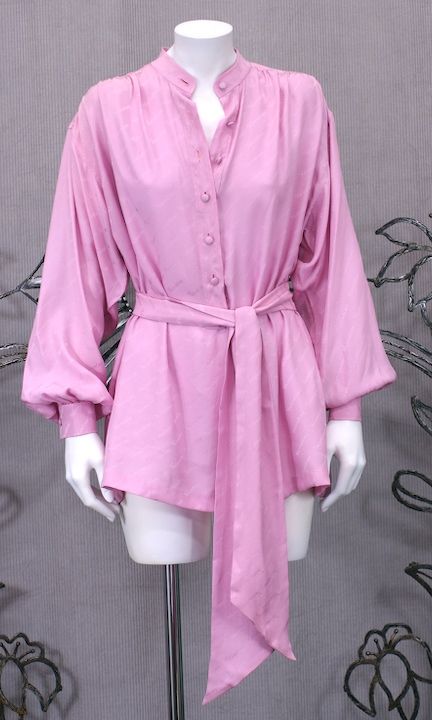 Lilac pink Valentino silk jacquard logo tunic/blouse with self sash/tie. Poet style shirt with band collar and gathered yoke front and back. Self covered buttons on front placket with hand overcast buttonholes. 