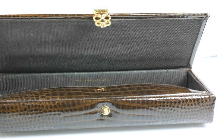 Leather clutch by Koret designed to resemble a Victorian glove box. The leather is embossed to look like shiny alligator with loopy gilt mounts. Very chic and unusual. Lined in black faille.<br />
Excellent condition 1950s USA.<br />
10