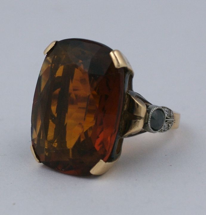 Oversized cushion cut citrine ring in deep cognac tones from the 1940s. The shoulders are accented with a black diamond and white diamond accented 