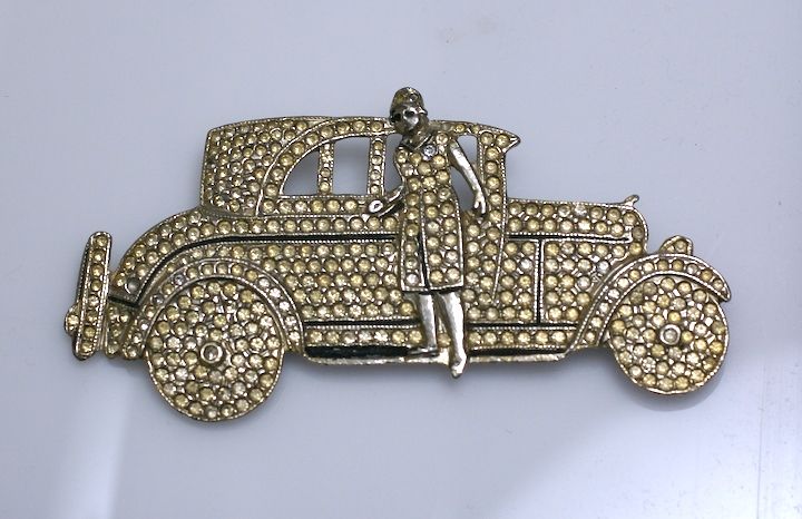 Unusual brooch of a period car with a flapper figure stepping off. Completely paveed in rhinestones. USA 1970s.<br />
Excellent condition.
