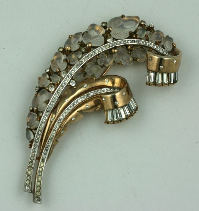 Large Trifari fur clip/brooch from the 1940s. Beautiful design with pave accents and retro curls with baguettes. Molded glass fruit in moonstone travel up the spine of the feather. Made in the Cartier style of tutti frutti jewelry. Amazing