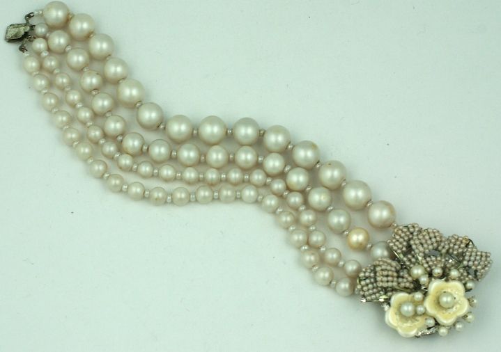 Miriam Haskell a élaboré quatre brins en argent doré et eau douce.<br />
Le fermoir orné de feuilles de perles de rocaille pavées, de fleurs de perles d'eau douce et d'étamines de perles, est un élément essentiel de la collection de perles de