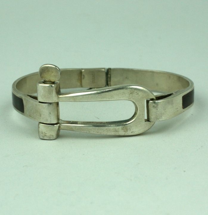 This large sized hinge bracelet is reminiscent of sterling and enamel Gucci designs from the 1970s. This sterling one is unsigned with very nice, heavy quality with brown enamelling on the band. Style suitable for men or women. Opens in back with