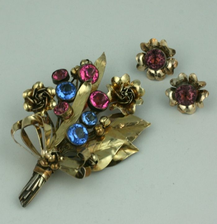 Handmade sterling and gilt sterling brooch set with colored bezel set paste stones by Hobe from the 1930s. Large spray of 2 toned leaves and flower buds with matching screw back fitted earrings.<br />
4