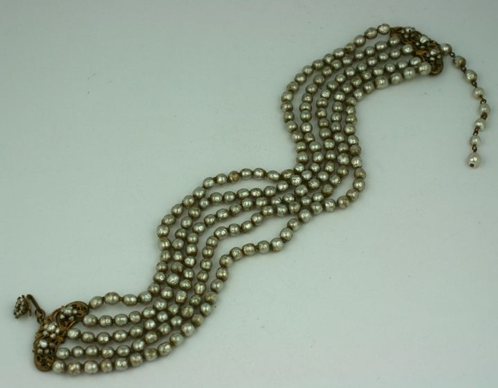 Miriam Haskell's classic five strand choker necklace of signature baroque pearls with adjustable pearl chain closure and russian gilt metal mounts. Hand wired pearl decoration on clasp.<br />
5 strand, 13