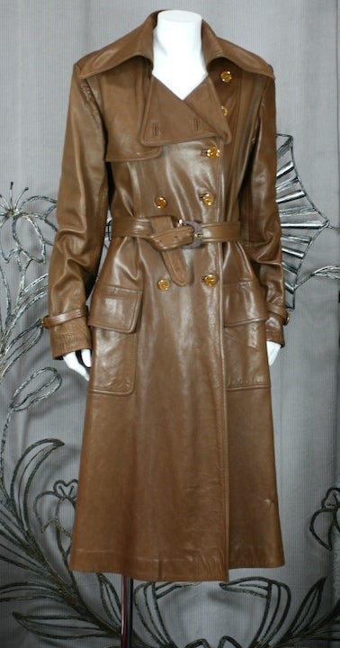 Luxurious caramel leather trench from Gucci, Italy circa 1970s.
Beautifully styled and cut. Crafted with all the Gucci embellishments Wood logo buckles at waist and wrists,enamel Gucci buttons down the front, and a Gucci logo within the lining. Size