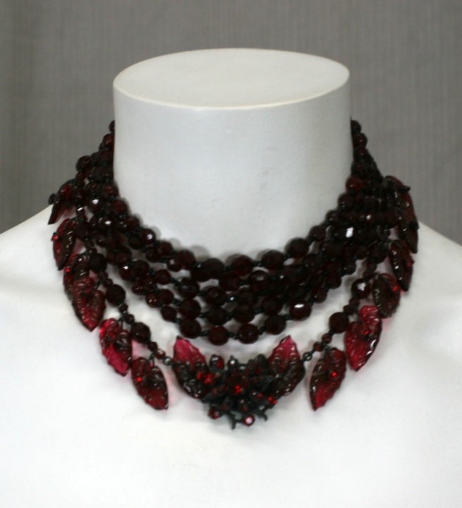 Important suite by Miriam Haskell of unusual ruby molded leaves. 5 strands of deep garnet faceted beads sit close to the neck. The last row is decorated with the ruby glass leaves with paste set rubies and a central manipulated motif. Set against