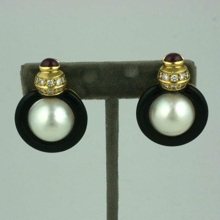 Large scaled ear clips with mabe pearls surrounded by onyx donuts. Pave diamonds and ruby cabochons accent the clip back earring. Heavy 18K gold setting. Beautiful quality.
Excellent condition. 1.5
