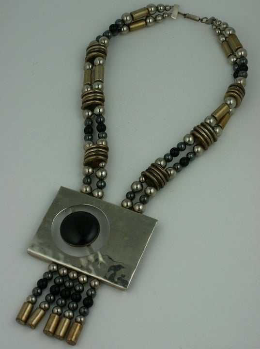 Una straordinaria collana con ciondolo in stile modernista. Onice nero cabochon su cromo martellato con distanziatori in ottone antico e perline in metallo.
Condizioni eccellenti.