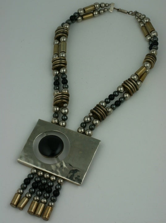 Striking Pendant necklace in the modernist style. Black onyx cabochon on hammered chrome with antique brass spacers and metal toned beads.
Excellent condition.