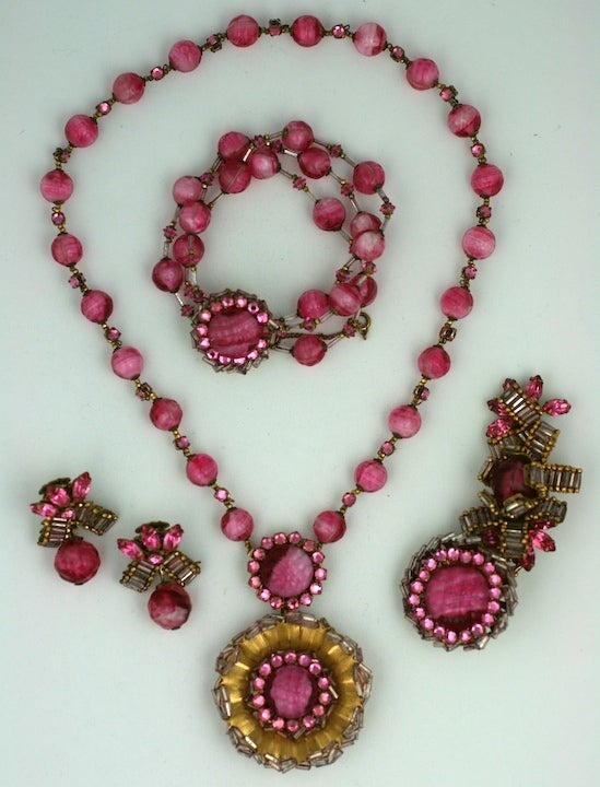 Wonderful and rare Miriam Haskell parure of Rosy pate de verre beads and pink pastes. Unusual configurations. Elaborately embroidered throughout with patinaed pink bugle beads.
Necklace with pendant, large brooch, drop earclips and triple strand