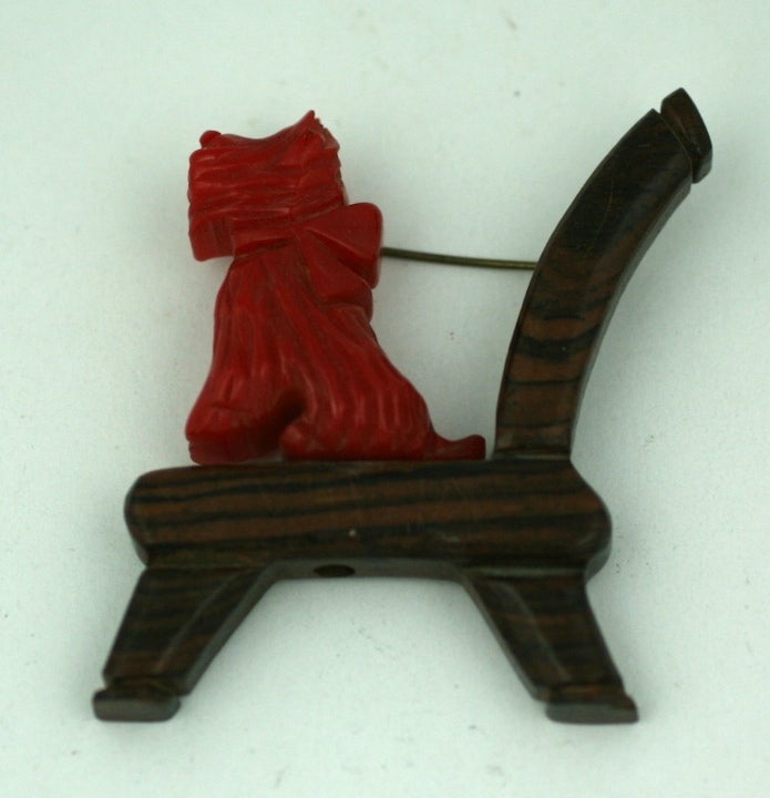Charming carved red bakelite terrier on a carved wood chair. Expectantly perched waiting for her biscuit, and bowed to boot. Anonymous bakelite jewelers created purely whimisical American folk art in the US in the 1930's.  2.5