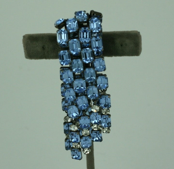 A double cascade of emerald cut faux aquamarines in an unusual configuration by Jacques Griffe. Stones are set so they peak out from underneath at different angles. Pastes are striking set against blackened metal. Clear pastes accents the edge.