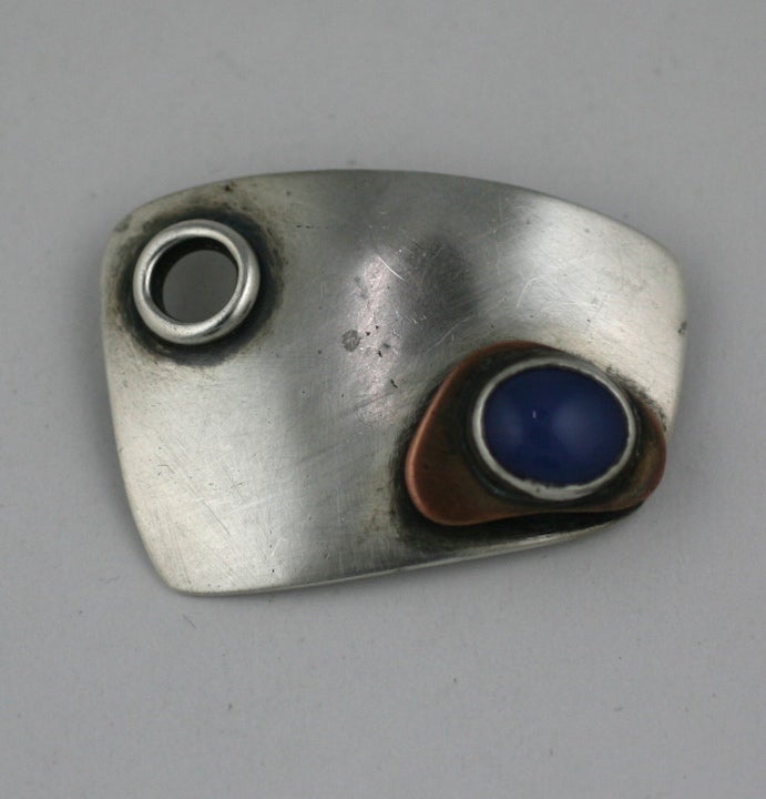 Miniature sculpture to wear by Modernist Sam Kramer. Brooch of sterling,copper and chalcedony with porthole and raised bezel set blue chalcedony atop a copper triangle. All have the patinaed shadows around motifs to create depth. 2