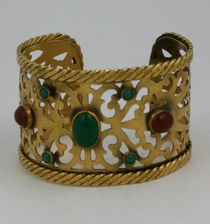 Elegant cuff by Yves Saint Laurent in the Byzantine taste of antique bronze pierce worked metal set with cabochon faux gems in carnelian and green onyx. Twisted metal banding trims the edges. 2