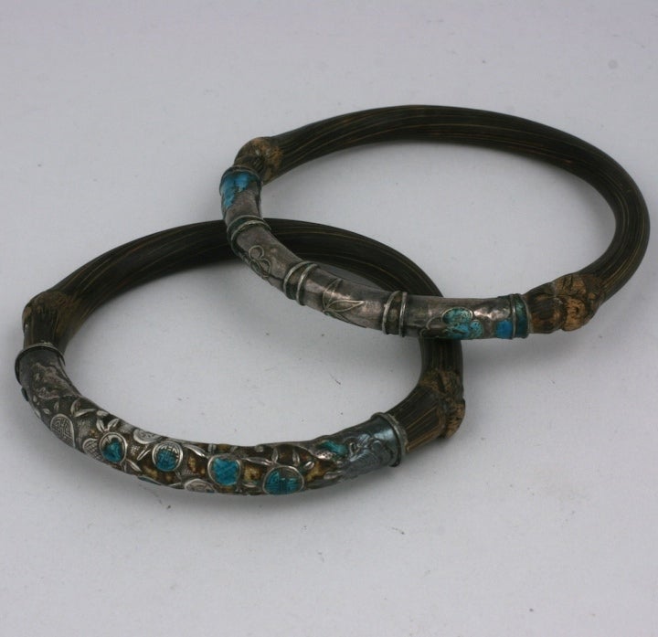 Pair of 19th Century Chinese Bangles of bamboo, silver and enamel. Traditional floral motifs are enameled in kingfisher blue on silver. Naturally formed bent bamboo forms the back of each bangle. Chinese 1900.
One is rounder and one is more