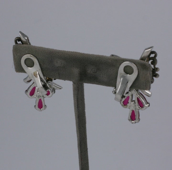 Marcel Boucher ruby and crystal retro earclips set in sterling silver. Dangling from a silver pave bow and gold and ruby pierced floral fan, are three  articulated ruby pear shaped drops. 1940s USA. Signed.  1