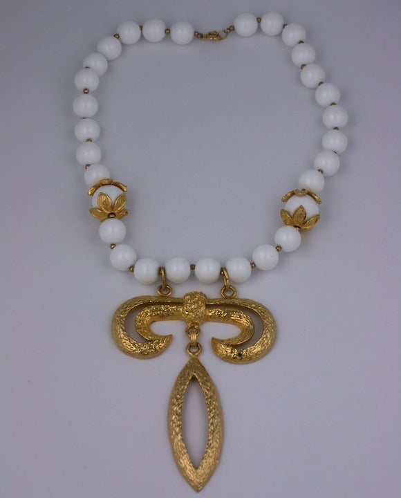 Attractive 1960s necklace with hammered gold pendant in the David Webb style. Large white resin beads with floriform gilt caps suspend a large grecian style pendant. 18