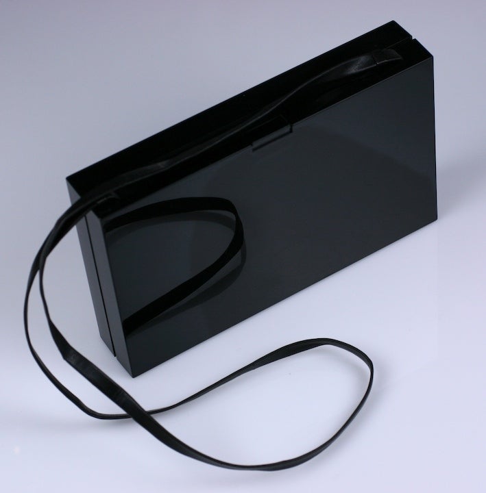 YSL Logo hard resin minaudiere/clutch with thin leather shoulder strip by Tom Ford. Thin profile with one mirrored side in the interior. Hidden closure clasp closure. Sleek and functional. 